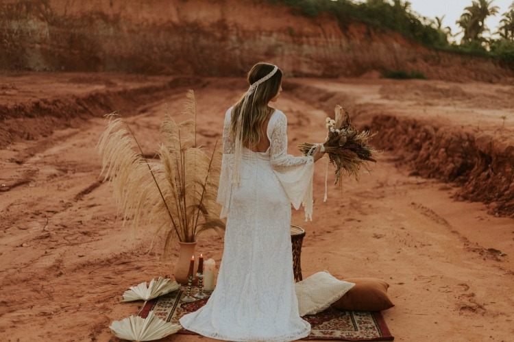 Eine Braut im Spitzenkleid in der Wüste auf einem Perserteppich und Dekoration