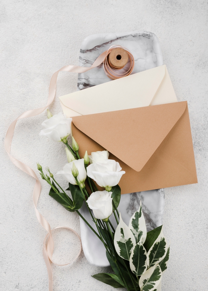 Hochzeitskarten mit braunen Briefumschlägen und weißen Rosen