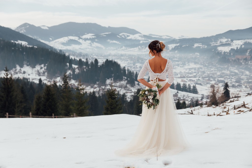 Eine Braut genießt die Aussicht auf verschneite Berge und Täler